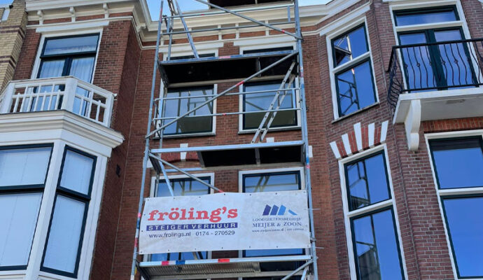 Een flat in de steigers van Fröling’s Totaalonderhoud met een grote spandoek van Fröling’s.